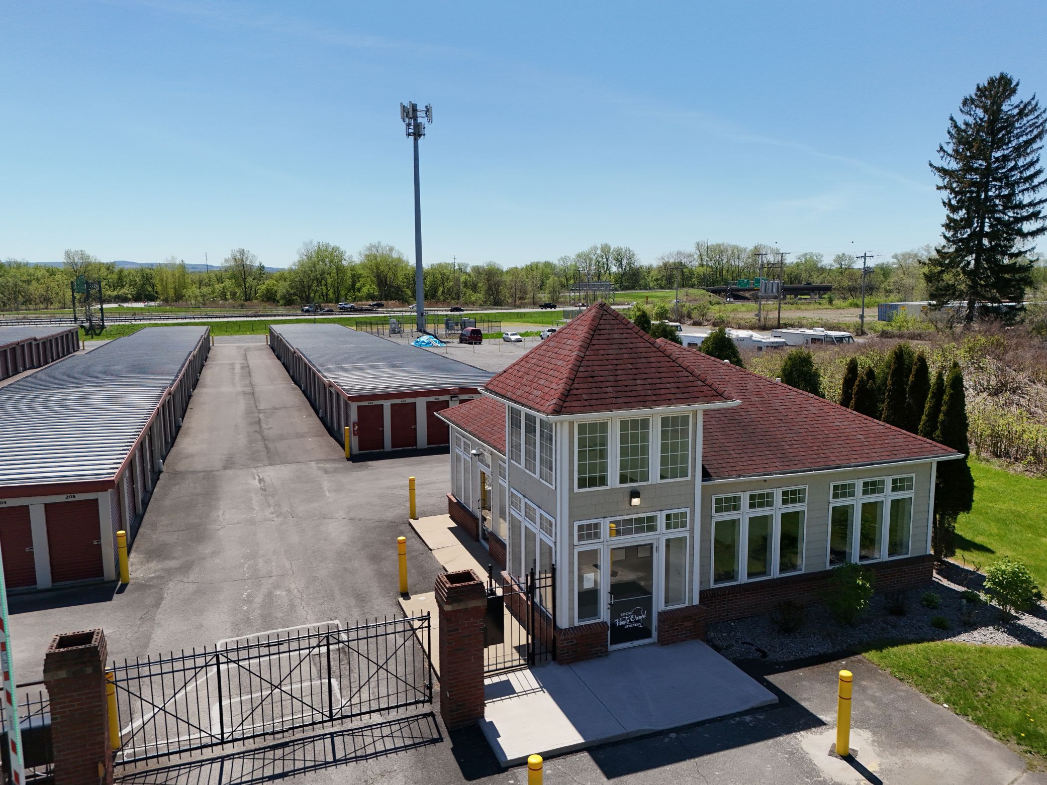 A-Verdi Self Storage office building and gated entrance with red storage units behind it.